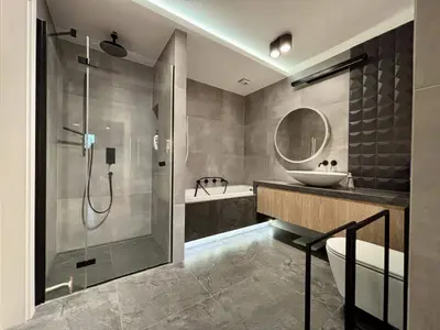 Nowoczesna łazienka z prysznicem walk-in, wanną zabudowaną, okrągłym lustrem i umywalką na szafce z drewna