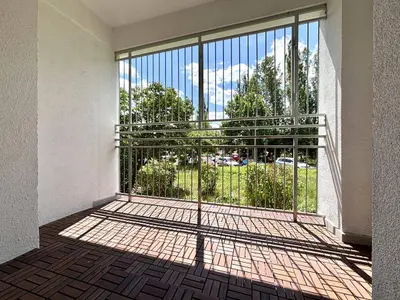 Loggia z kratownicą metalową i widokiem na park, kafelki antypoślizgowe na balkonie