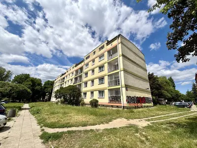 Widok zewnętrzny pięciopiętrowego bloku z zielenią wokół, Łódź-Żubardź