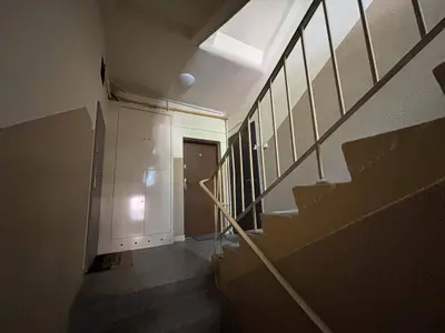 Klatka schodowa bloku z drzwiami do mieszkań i betonowymi schodami oświetlona naturalnie