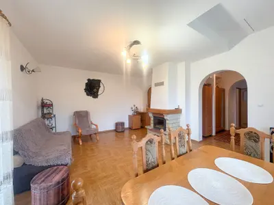 Salon z kominkiem, drewnianą podłogą i łukiem w domu w Brogach