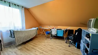 Duży pokój na poddaszu z pomarańczowymi ścianami, skosami i suszarnią na pranie