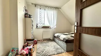 Pokój dziecięcy na poddaszu ze skosami, łóżkiem pojedynczym i zabawkami na regale