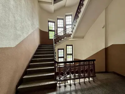 Reprezentacyjna klatka schodowa z kutą balustradą i przeszklonymi oknami w kamienicy