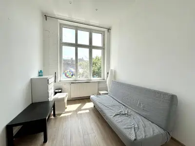 Mały pokój z sofą, stolikiem i oknem z widokiem na drzewa – kamienica przy Kościuszki