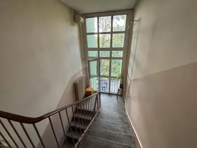 Klatka schodowa z dużym oknem i widokiem na zieleń — budynek Łódź-Zarzew 46 m²
