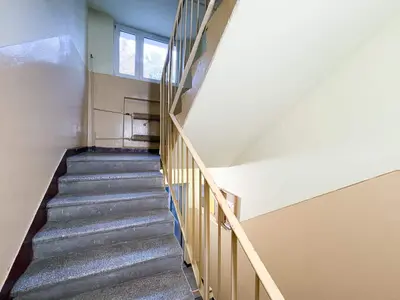 Widok schodów w budynku mieszkalnym z metalowym poręczem i jasnymi ścianami. mieszkanie na sprzedaż Łódź Retkinia - Florecistów