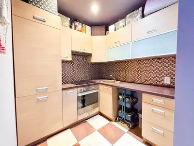 Kuchnia z szafkami z jasnego drewna, wbudowanym piekarnikiem, mozaikowym backsplash i ciemnymi blatami