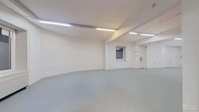 Duże otwarte pomieszczenie biurowe z szarą posadzką i oświetleniem fluorescencyjnym