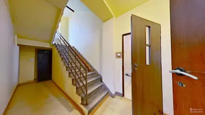 Klatka schodowa kamienicy z metalową balustradą i żółtymi ścianami — Łódź Bałuty