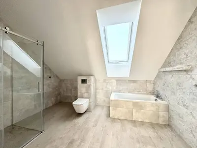 Łazienka na poddaszu z oknem połaciowym, wanną i przeszkloną kabiną prysznicową