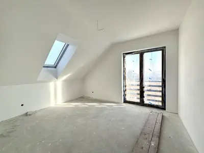 Pomieszczenie na piętrze ze skośnym sufitem, oknem dachowym i wyjściem balkonowym