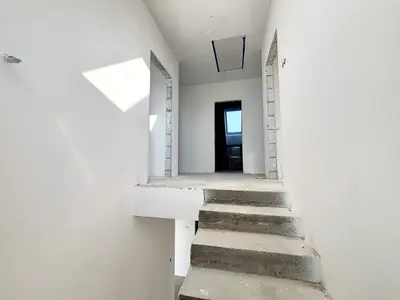 Surowa klatka schodowa z betonowymi stopniami i otwartymi otworami drzwiowymi