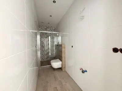 Łazienka w stanie deweloperskim z kabiną prysznicową i podwieszaną muszlą klozetową