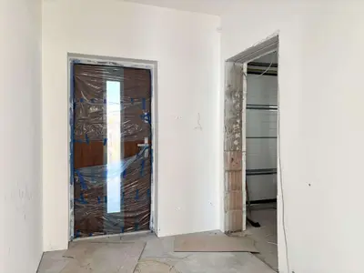 Przedsionek w stanie deweloperskim z drzwiami wejściowymi w folii ochronnej