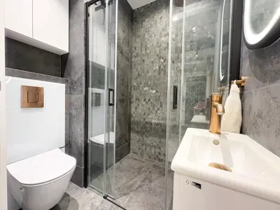 Druga łazienka z kabiną prysznicową i kamiennymi płytkami w odcieniach szarości