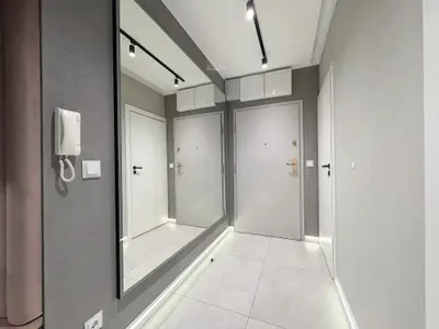 Jasny korytarz wejściowy z dużym lustrem i białymi drzwiami — Łódź Śródmieście