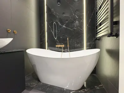 Wolnostojąca biała wanna na tle czarnego marmuru z podświetleniem LED