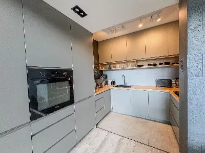 Kuchnia w zabudowie z szarymi frontami i drewnianym blatem w domu we Wronowicach