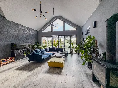 Salon z duÅ¼ymi przeszkleniami trÃ³jkÄtnymi i kominkiem wolnostojÄcym w domu we Wronowicach