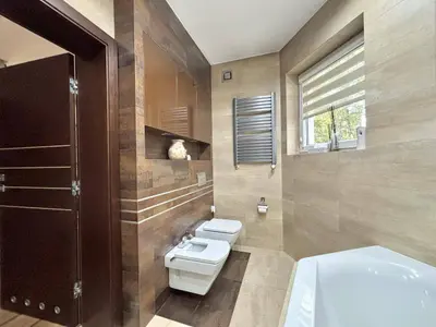 Druga łazienka z wiszącą miską WC, bidetem, grzejnikiem drabinkowym i wanną narożną