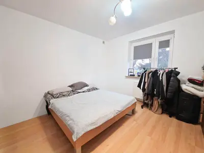 Sypialnia z łóżkiem i wieszakiem na odzież, jasny parkiet