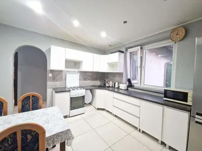 Duża kuchnia z białą zabudową i blatem, okno na ogród w domu Swędów