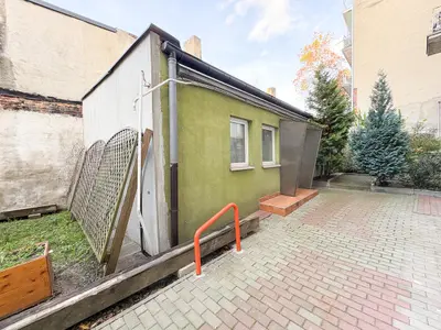 Zielony parterowy budynek z oknami na wybrukowanym podwórku — Łódź Bałuty